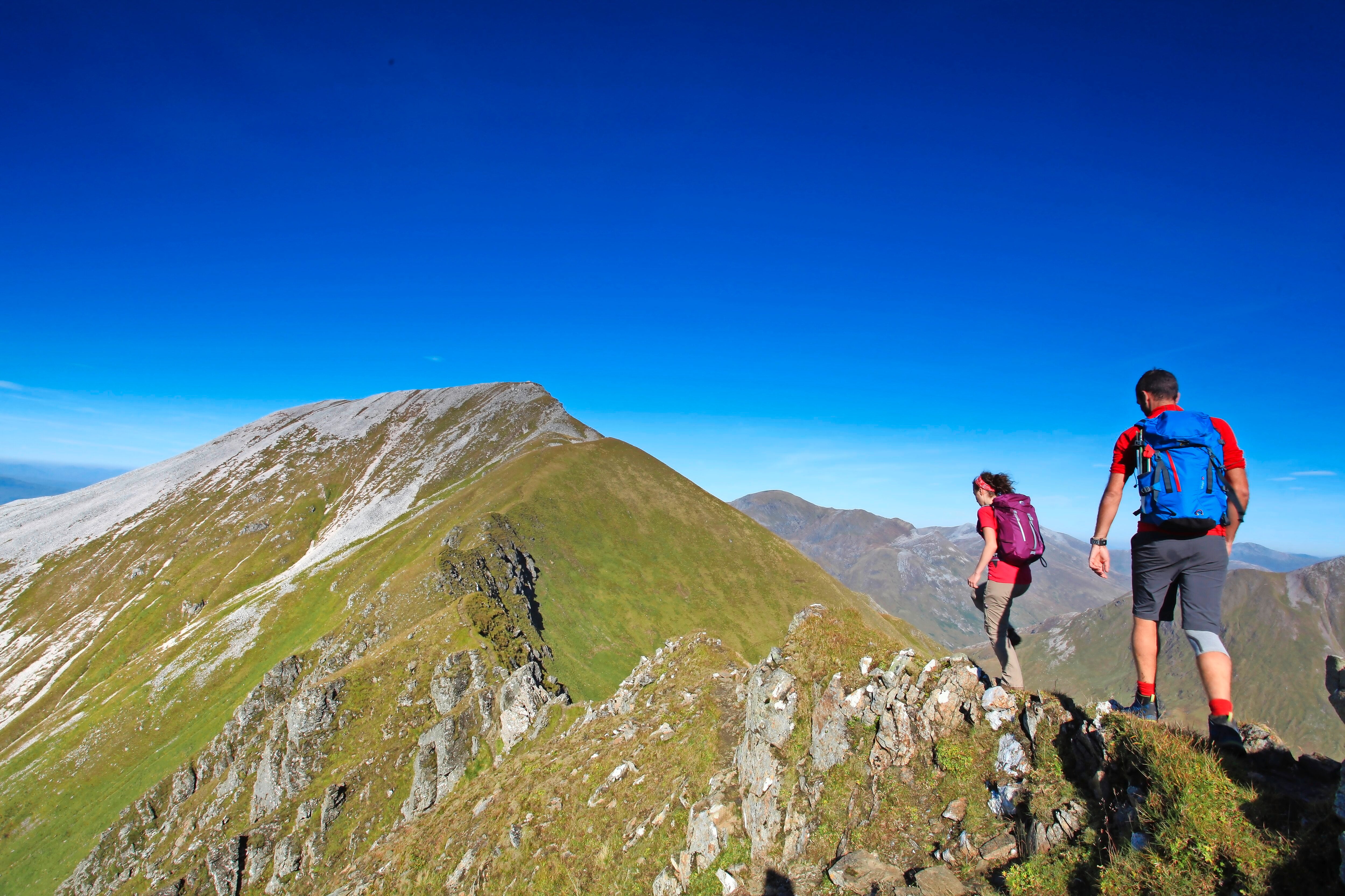 Two hikers on a mountain peak with clear blue sky