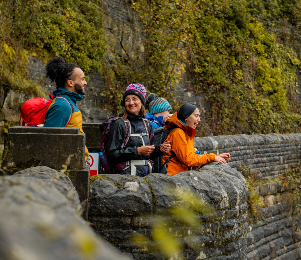 Group of people sitting on a stone wall with a scenic background