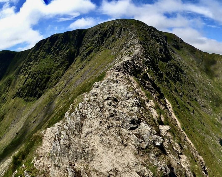 Mountain peak with a rocky trail and a lake in the background