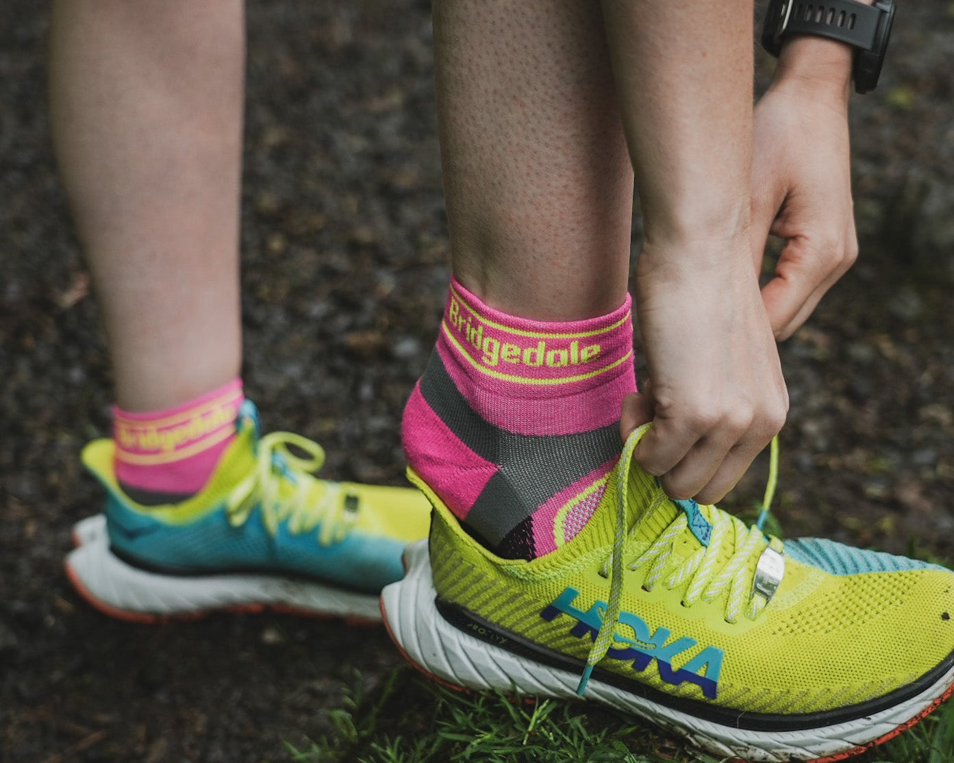 Person tying bright yellow running shoes with colorful socks on a natural background